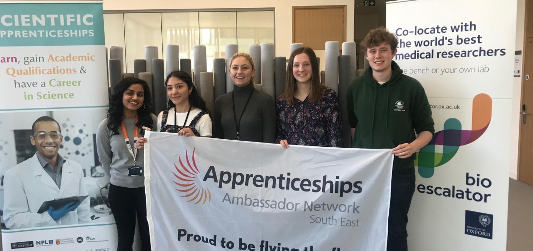 University laboratory technician apprentices holding the Apprenticeship ambassador flag during National Apprenticeship Week 2019