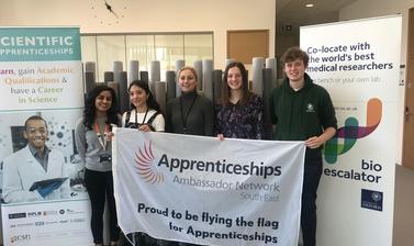 University laboratory technician apprentices holding the Apprenticeship ambassador flag during National Apprenticeship Week 2019